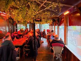 Vol overdekt terras bij feestzaal Oud Vrienden op een avond, met gasten onder de terrasverwarmers